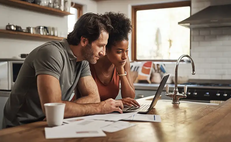 Couple in a kitchen on a laptop applying for Home Equity Line of Credit (HELOC)