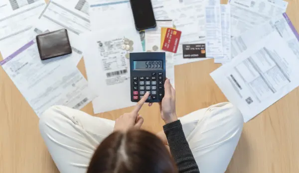 Sitting woman calculating debts with bills and credit cards on the floor, before applying for a personal loan